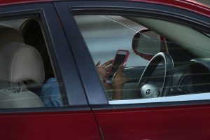 A driver uses a phone while behind the wheel of a car 