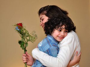  Little boy hugging mom with beautiful flower rose