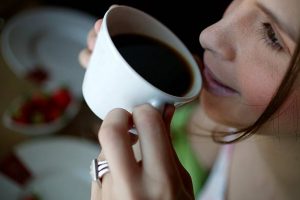 A woman drinking a cup of black coffee
