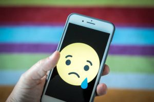 A sad face emoticon is seen on an iPhone