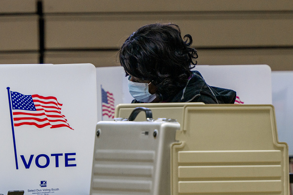 african american womn with mask on sitting at a table voting in an election Get Out and Vote Black Party in Detroit